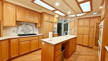 A kitchen with wooden cabinets, a central island, a microwave, and a sink.
