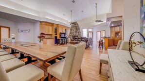 A spacious living area with a large wooden dining table, comfortable seating, and a stone fireplace. - Villa with indoor pool in Temecula wine country-VRBO (Temecula)