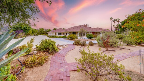 A house with a curved driveway, surrounded by various plants and trees. - Villa with indoor pool in Temecula wine country-VRBO (Temecula)