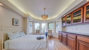 A bedroom with a large bed, a wooden cabinet, and a view of the outdoors. - Villa with indoor pool in Temecula wine country-VRBO (Temecula)