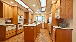 A spacious kitchen with wooden cabinets, a central island, and built-in appliances. - Villa with indoor pool in Temecula wine country-VRBO (Temecula)