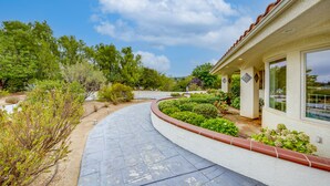 A curved pathway leading to a building with a tiled roof and a garden area with various plants and shrubs. - Villa with indoor pool in Temecula wine country-VRBO (Temecula)