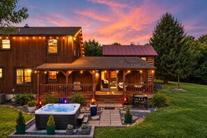 Una casa de madera de dos pisos con un porche, jacuzzi y zona de estar al aire libre.