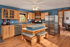 Une cuisine avec des meubles de rangement en bois, un réfrigérateur en acier inoxydable et un plan de travail bleu.