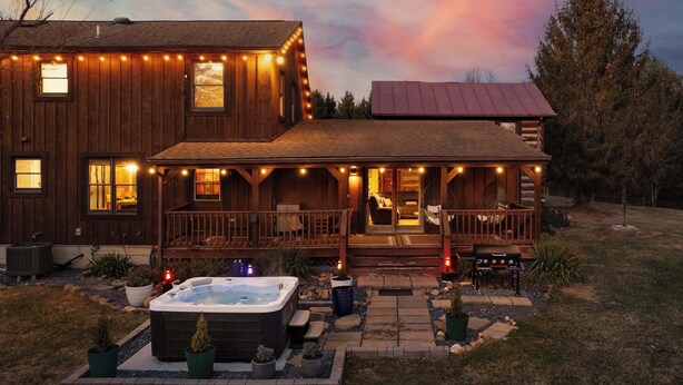 Ein Holzhaus mit Veranda, Whirlpool und einer Terrasse.