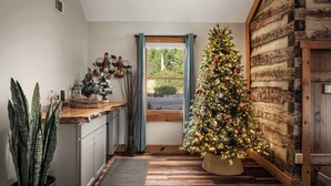 Eine gemütliche Küche mit Holzbalkenwand, einem Weihnachtsbaum und einem Fenster mit blauen Vorhängen.