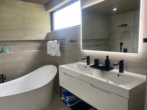 Ein modernes Badezimmer mit einer freistehenden Badewanne, zwei Waschbecken und einem großen Spiegel.