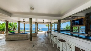 A covered outdoor area with a bar, seating, and a view of the sea.