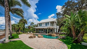 A two-story house with a pool, surrounded by palm trees and a well-maintained lawn.