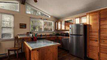 Una cocina con armarios de madera, un refrigerador de acero inoxidable y una ventana con persianas.