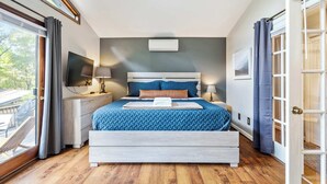 Un dormitorio con una cama grande, una mesita de noche, un televisor y una ventana con cortinas.
