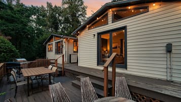 Una terraza con mobiliario exterior, una parrilla y un interior acogedor con chimenea.