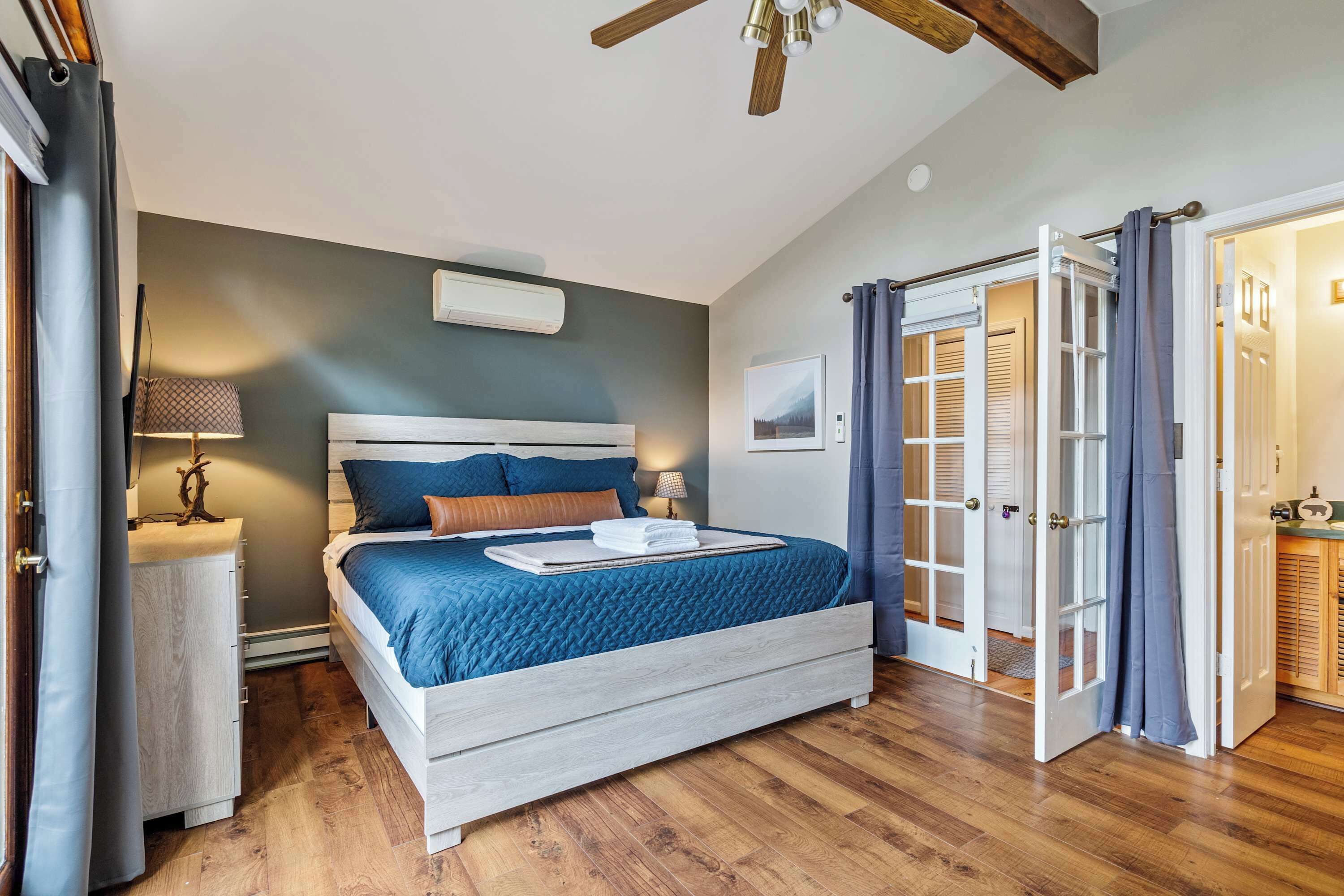 A bedroom with a bed, bedside table, lamp, and a ceiling fan.
