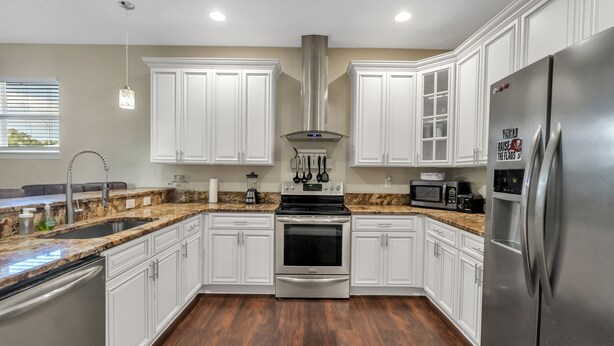 A modern kitchen with white cabinets, stainless steel appliances, and a granite countertop. - Centrally Located Spacious 3 BR Home (Tampa)