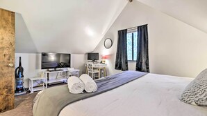 Une chambre à coucher avec un lit, un bureau, une télévision et une fenêtre avec des rideaux.
