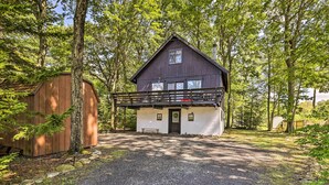 Une cabane à deux étages dotée d’un porche abrité, entourée d’arbres.