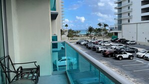 A balcony with a view of a parking lot and a building with multiple floors and balconies.