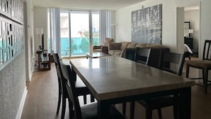 A modern living room with a dining area, a large window with a view, and a ceiling light.