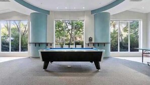 A pool table in a room with large windows and a high ceiling.