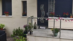 A building with a dark door, windows with shutters, and various potted plants on the exterior. - Stylish house near Paris 8 University (Pierrefitte-sur-Seine)