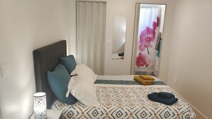 A bedroom with a bed, a nightstand, a lamp, a mirror, and a window with curtains. - Stylish house near Paris 8 University (Pierrefitte-sur-Seine)