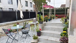 A patio with a table and chairs, potted plants, and a staircase leading to a higher level. - Stylish house near Paris 8 University (Pierrefitte-sur-Seine)