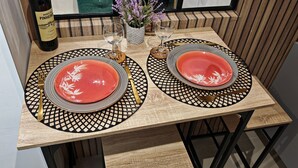 A dining table set with two plates, cutlery, and a bottle of wine. - Stylish house near Paris 8 University (Pierrefitte-sur-Seine)