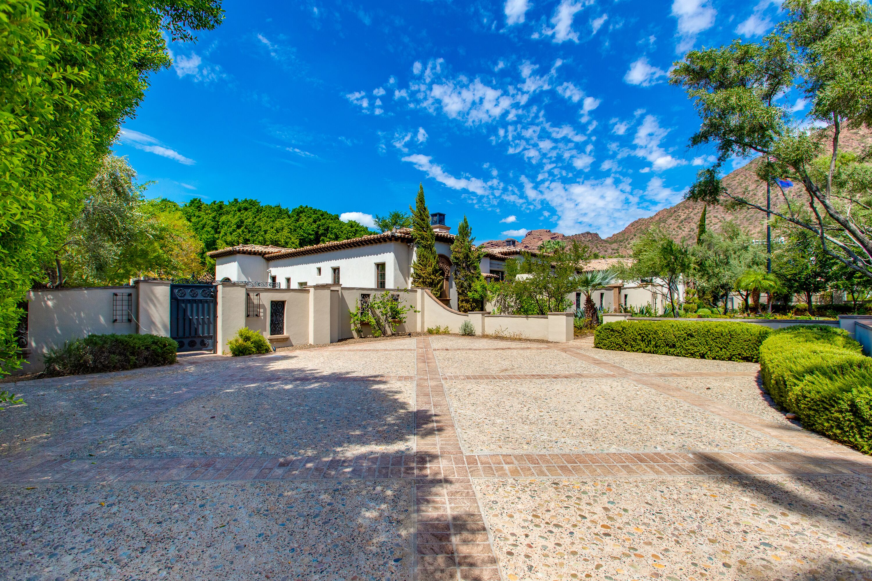 A spacious courtyard with a paved walkway, surrounded by buildings with traditional architecture and lush greenery.