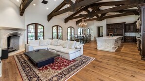 Ein geräumiges Wohnzimmer mit Kamin, weißem Sofa und einem großen Teppich.