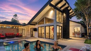 A modern house with a swimming pool, large windows, and a covered patio area.