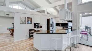 A modern kitchen with white cabinetry, a central island, and a large window providing natural light.