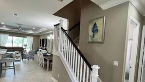 A spacious living area with a staircase, a dining area, and a large window. - Stunning Executive Home in Gated Community (Fort Myers)