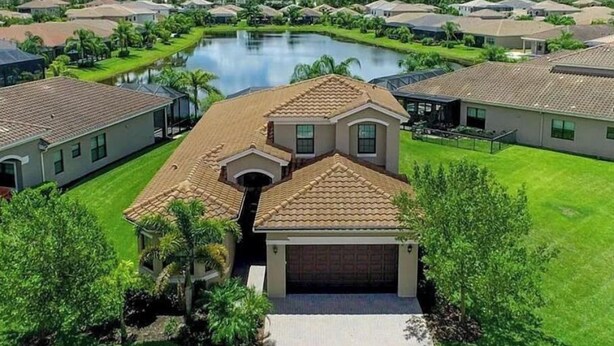 A residential area with houses, a lake, and well-maintained lawns. - Stunning Executive Home in Gated Community (Fort Myers)