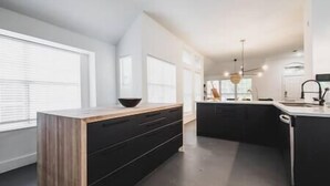 Eine moderne Küche mit einer Holz Arbeitsplatte, schwarzen Schränken und einem großen Fenster, das für natürliches Licht sorgt.