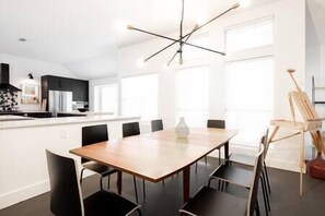 Una cocina moderna con una isla central, sillas negras y una mesa de comedor de madera.