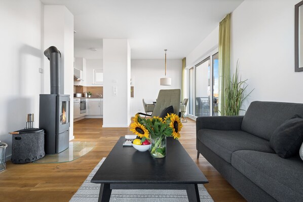 A modern living room with a sofa, a glass coffee table, and a fireplace. - Sea view vacation apartment directly on the Baltic Sea - 3 minutes walk to the beach (Olpenitz)