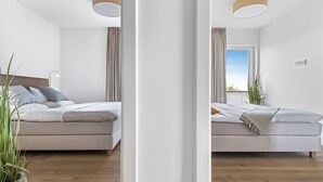 Un dormitorio moderno con cama, lámpara de noche y vistas al exterior.
