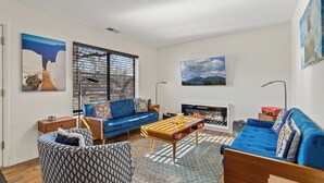A modern living room with a blue sofa, a patterned armchair, and a wooden coffee table.