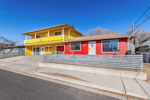Un bâtiment à deux étages, avec une façade jaune et rouge, une entrée principale et un banc devant.