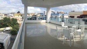 Ein Balkon mit Blick auf die Stadt, weiße Kunststoffstühle und ein Fliesenboden.