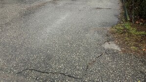 Um espaço de estacionamento com um edifício branco, um celeiro vermelho e uma cerca.