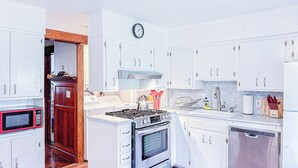 Uma cozinha compacta com armários brancos, micro-ondas, fogão e máquina de lavar louça.