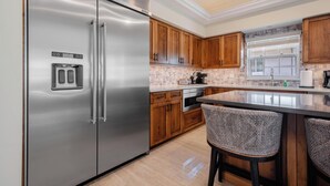 Eine moderne Küche mit Edelstahlgeräten, Holzschränken und einer Bar mit gepolsterten Hockern.