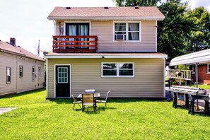A two-story house with a front porch, a small deck, and a lawn.