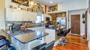 A modern kitchen with a central island, white cabinets, and a wooden accent wall.