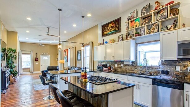 A modern kitchen with a central island, white cabinetry, and a variety of decorative items on the walls.