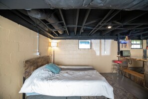 A room with a bed, a desk, a chair, and a neon sign.