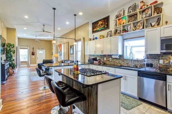 Una cocina moderna con una isla central, taburetes de bar y una zona de comedor con sofá.