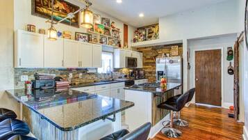A modern kitchen with a central island, white cabinets, and a wooden accent wall.