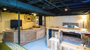 A cozy basement living space with a curved sofa, a wooden table, and a TV.